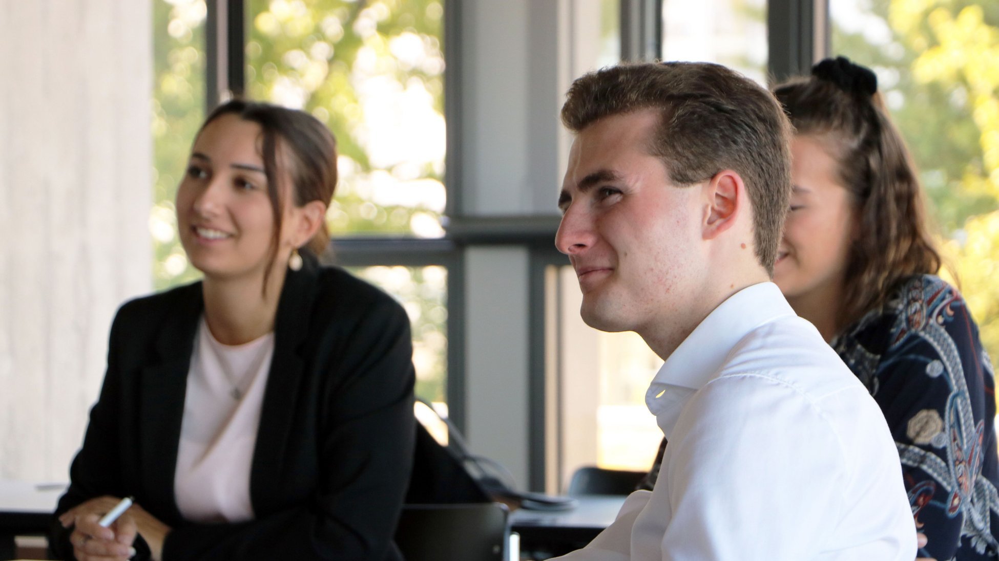 Three university students listening attentively and engaged during an interactive session of the HSG Banking Days.