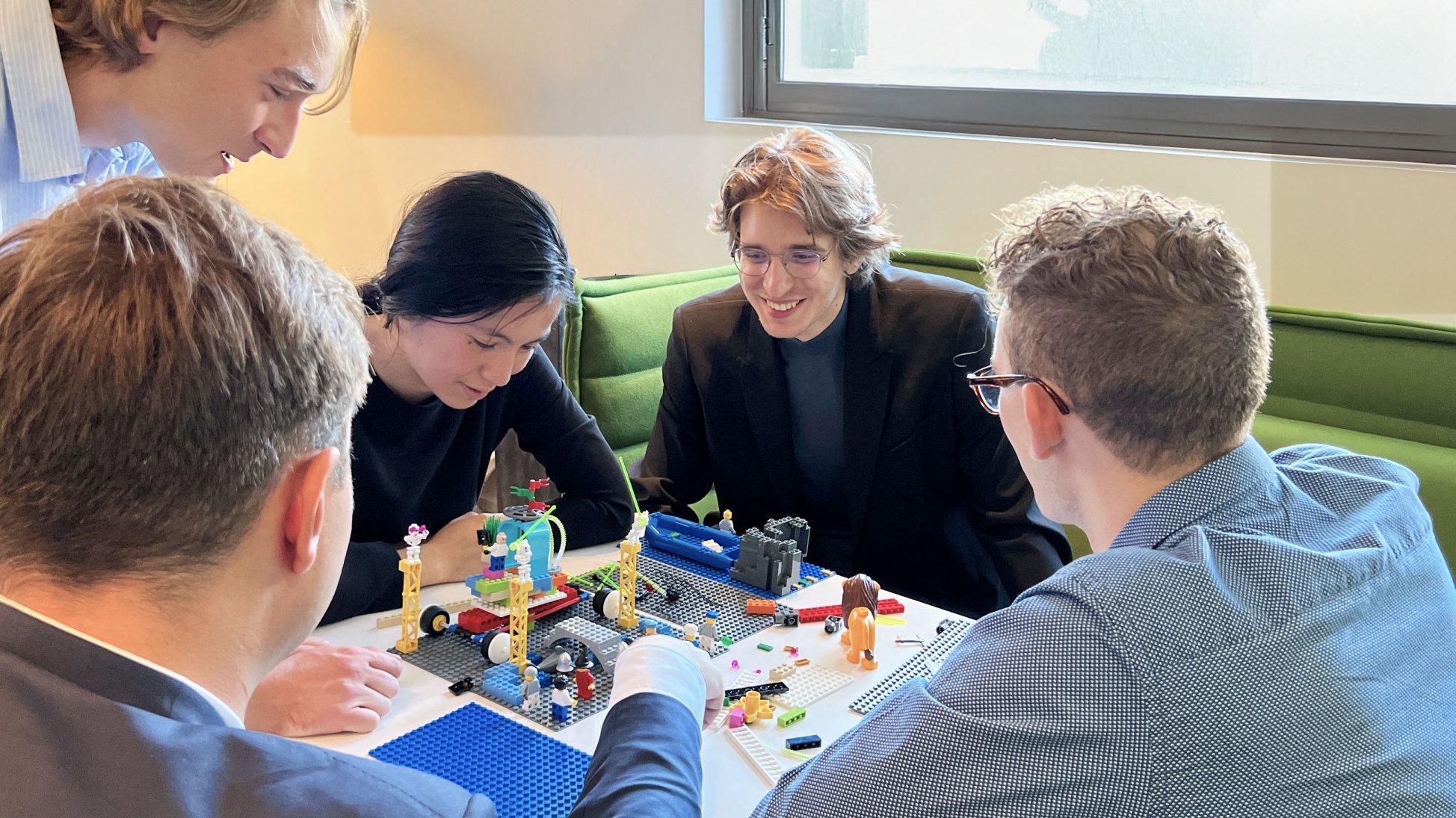 Group of students working together on LEGO models during a creative workshop session.